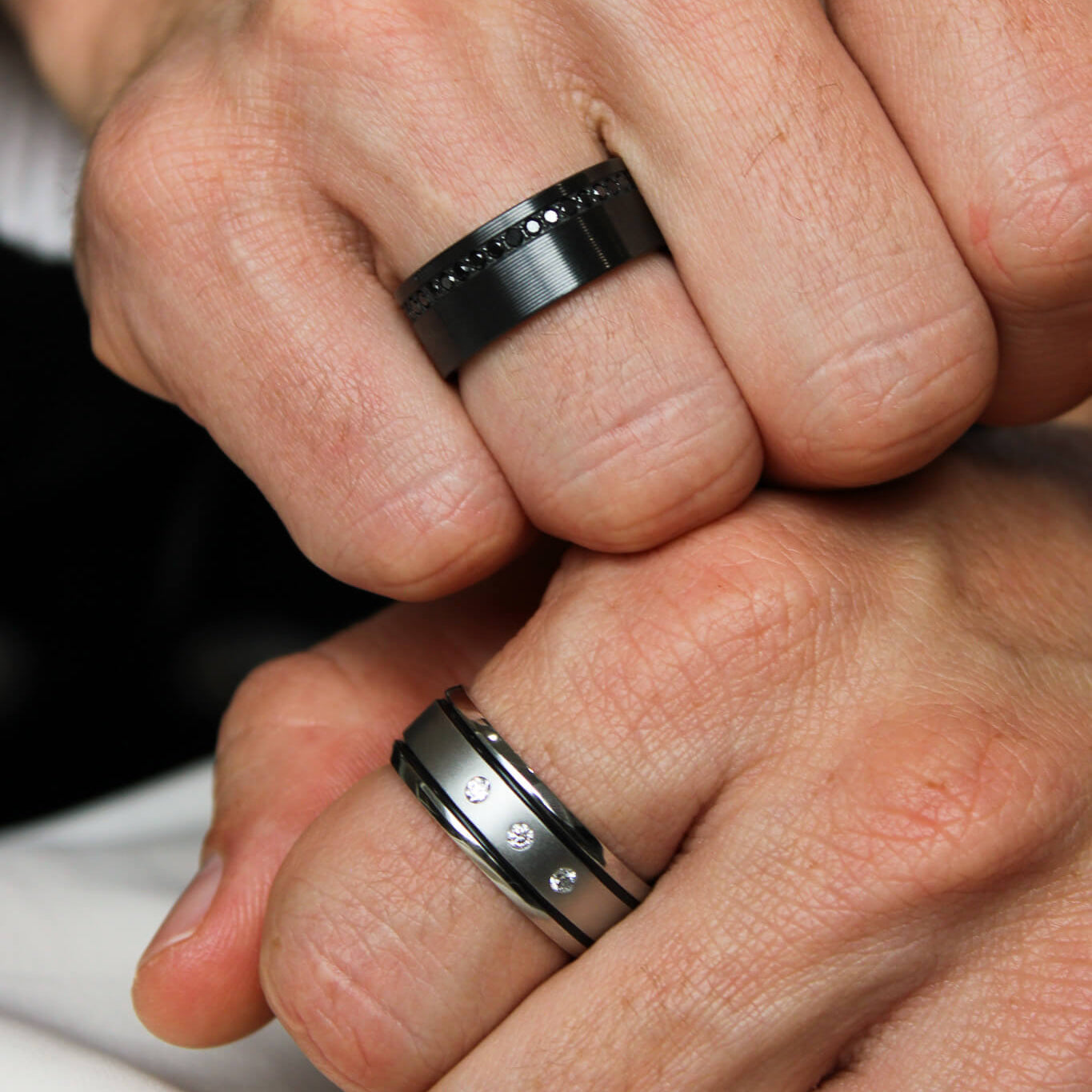 Cobalt chrome mens band with 3 lab grown diamonds and a two black inlays and black zirconium mens band on a man's hand.