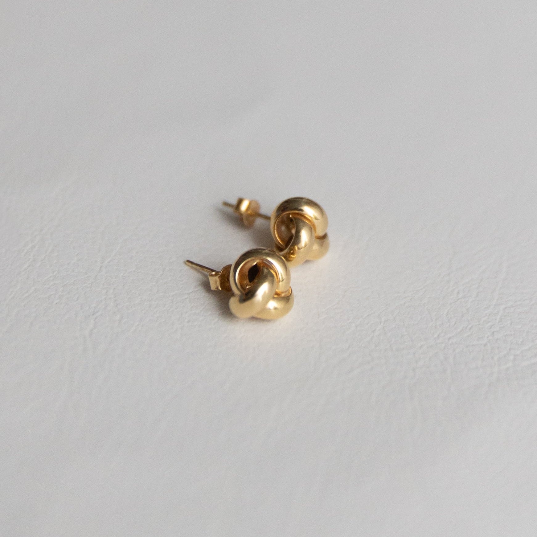 14K Gold love knot earrings on a light gray background