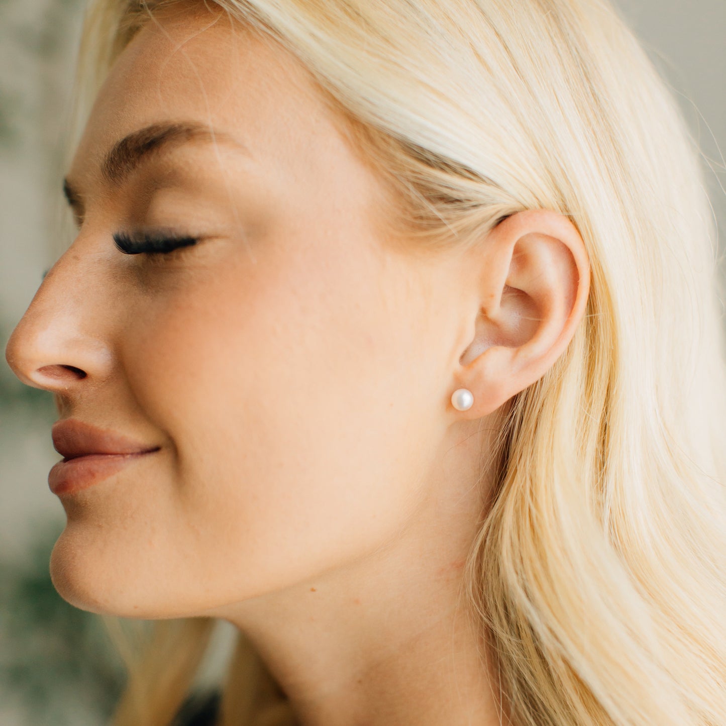 Close-up of a woman wearing a pearl earring with a blurred background