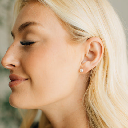 Close-up of a woman wearing a pearl earring with a blurred background