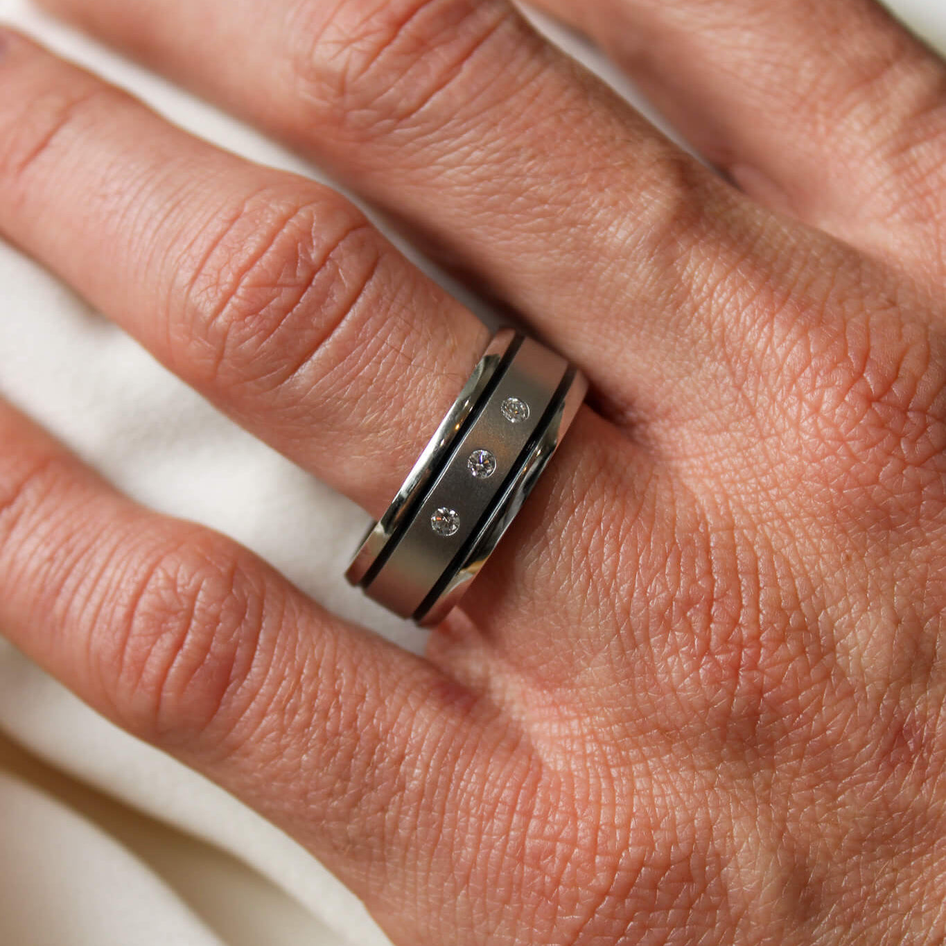 Cobalt chrome mens band with 3 lab grown diamonds and a two black inlays on a man's hand.