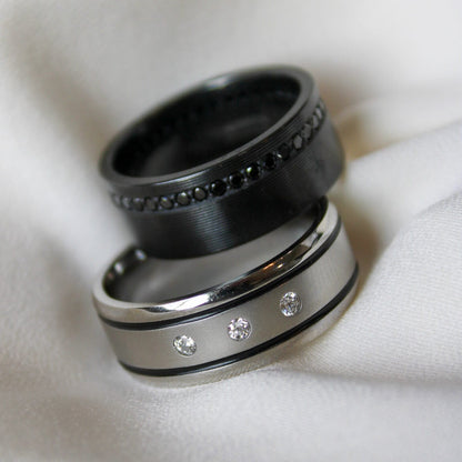 Cobalt chrome mens band with 3 lab grown diamonds and a two black inlays and a black zirconium ring with black lab grown diamonds on a white background.
