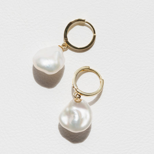 Pair of pearl earrings with gold hooks on a white background