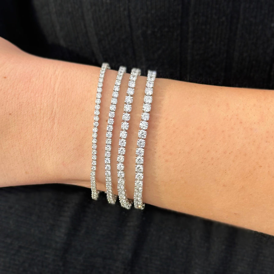 A person's wrist wearing a sparkling diamond tennis bracelets with white gold settings.