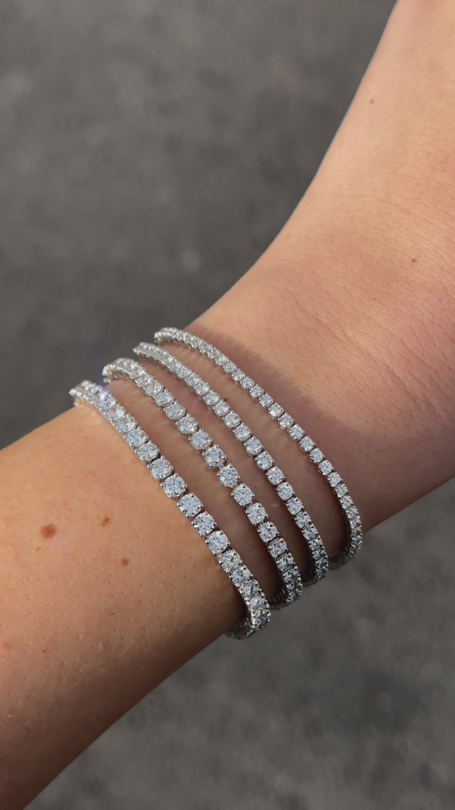 14k white gold tennis bracelets on a white woman's arm with a gray background. 2, 3, 5 and 7 carat bracelets. 